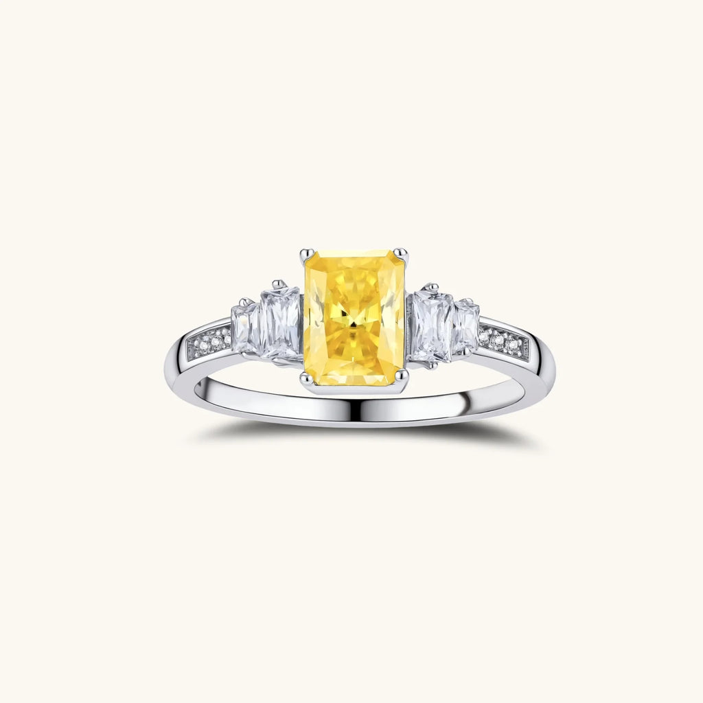 Sterling silver ring with emerald-cut yellow moissanite center stone and clear baguette side stones in elegant setting