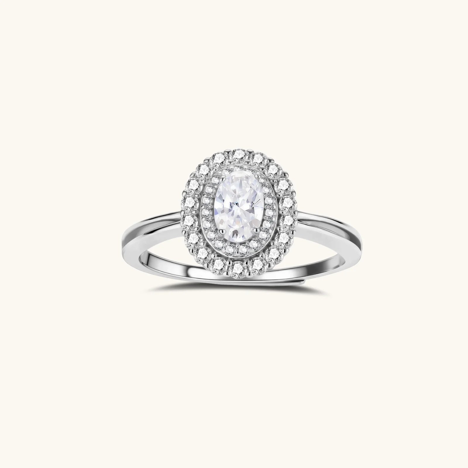 Sterling silver ring with oval moissanite center stone surrounded by double halo of sparkling stones on neutral background.