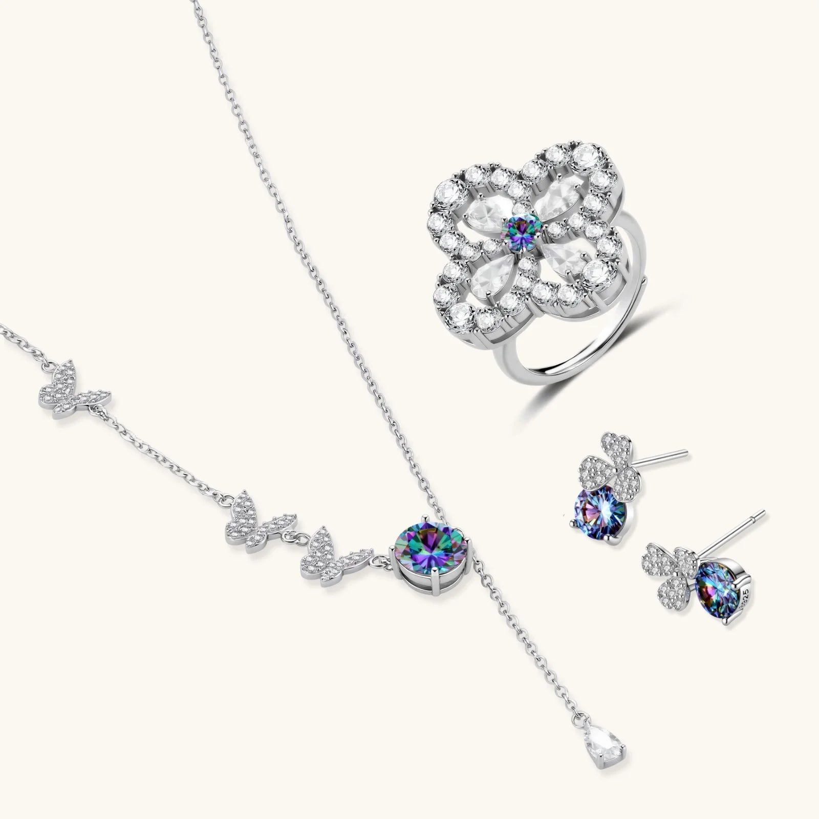 Sterling silver jewelry set with rainbow moissanite stones in clover and butterfly designs on cream background