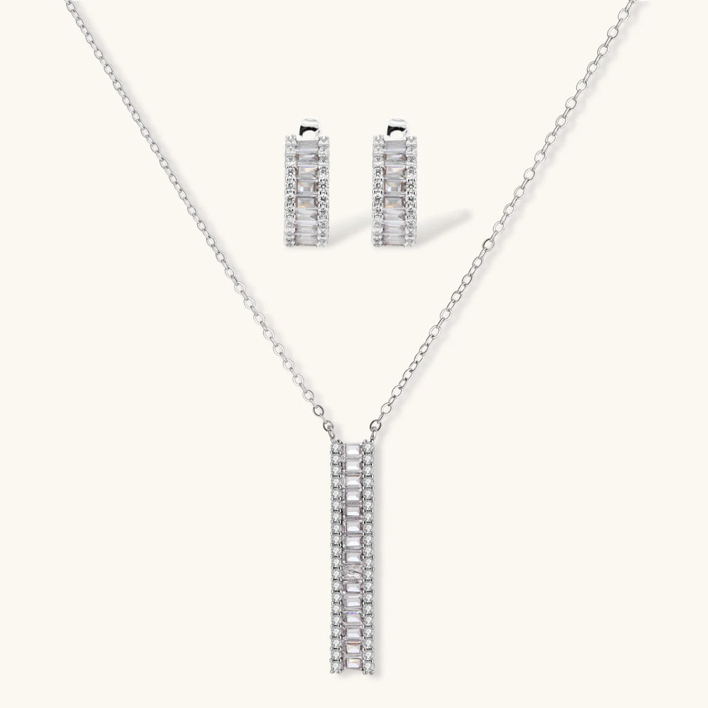White gold plated necklace with vertical cubic zirconia pendant and matching hoop earrings on neutral background