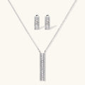 White gold plated necklace with vertical cubic zirconia pendant and matching hoop earrings on neutral background