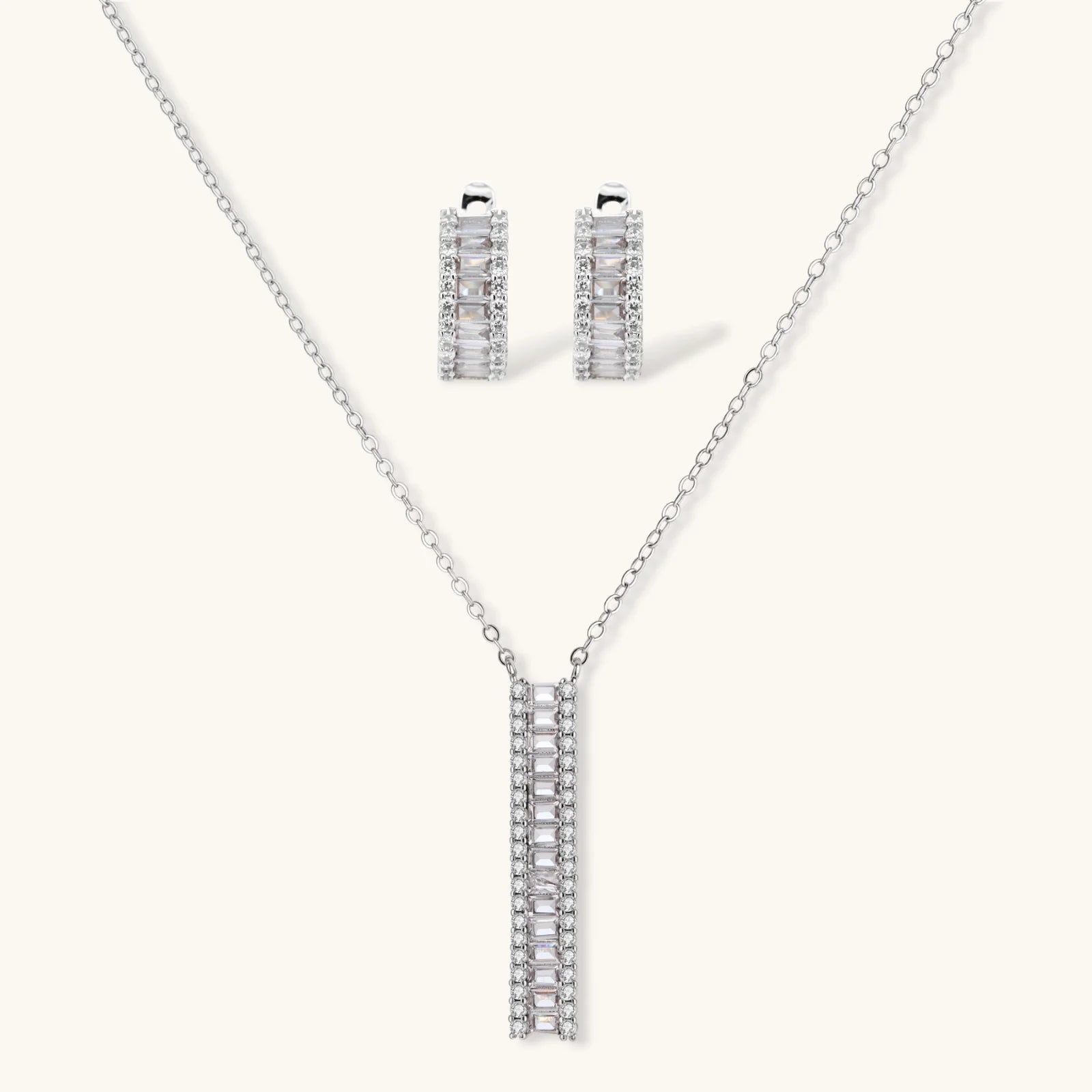White gold plated necklace with vertical cubic zirconia pendant and matching hoop earrings on neutral background