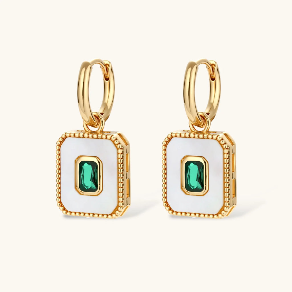 Gold-plated jewelry set with white enamel square pendants and emerald CZ stones on cream background.