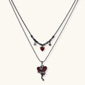 Dark layered necklace set with black chains and red heart pendants, featuring gothic snake design on white background