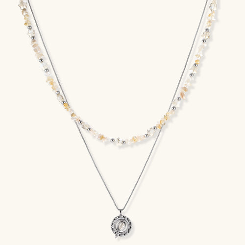 Two-layer necklace with natural stone chips and eco-brass beads, featuring a circular wrapped pendant on cream background.