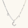 Silver-toned crescent moon pendant with star accents on pearl and chain necklace against white background.