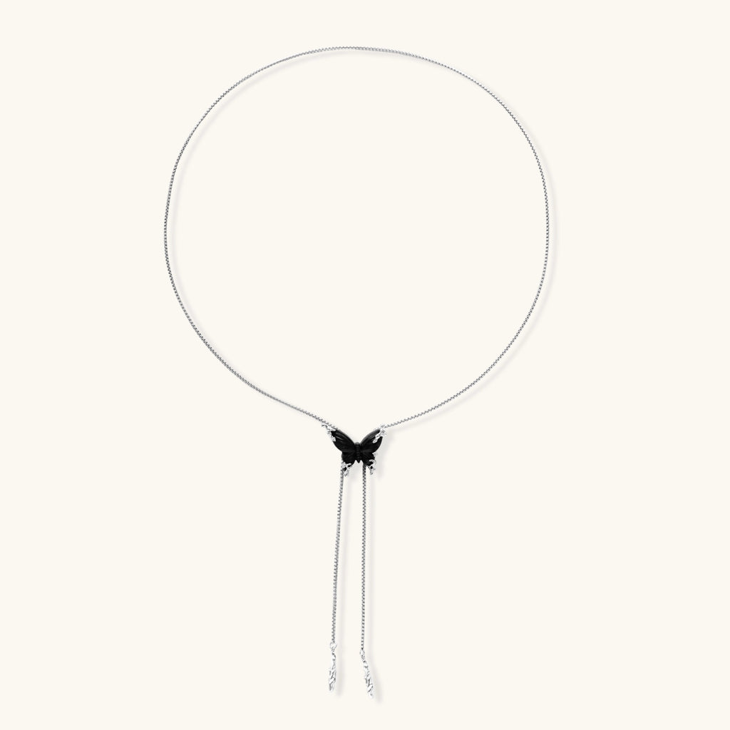 Wooden butterfly pendant necklace with cascading silver-toned chains on adjustable chain, available in amber and black.