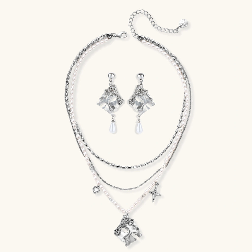 Ornate silver-toned masquerade mask jewelry set featuring rhinestone details and pearl drop earrings on white background.