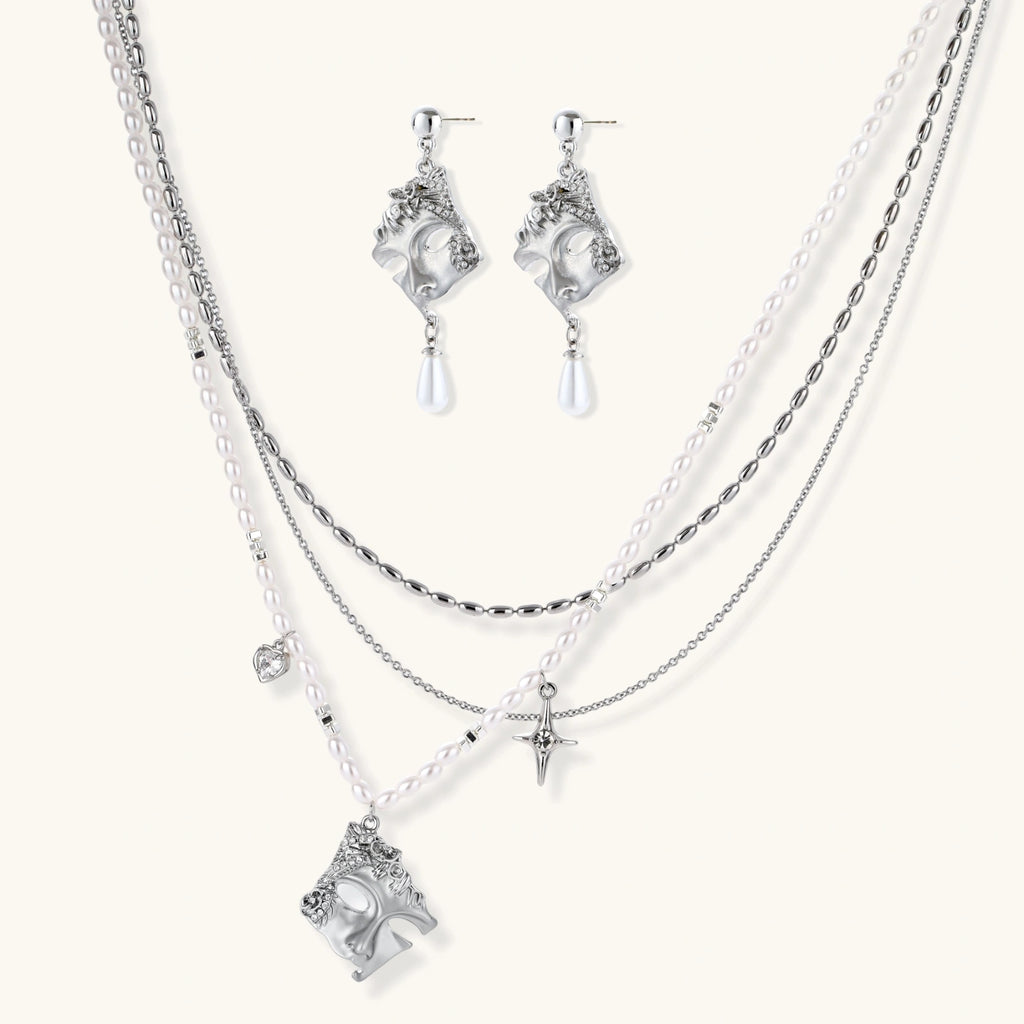 Ornate silver-toned masquerade mask jewelry set featuring rhinestone details and pearl drop earrings on white background.