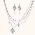 Ornate silver-toned masquerade mask jewelry set featuring rhinestone details and pearl drop earrings on white background.