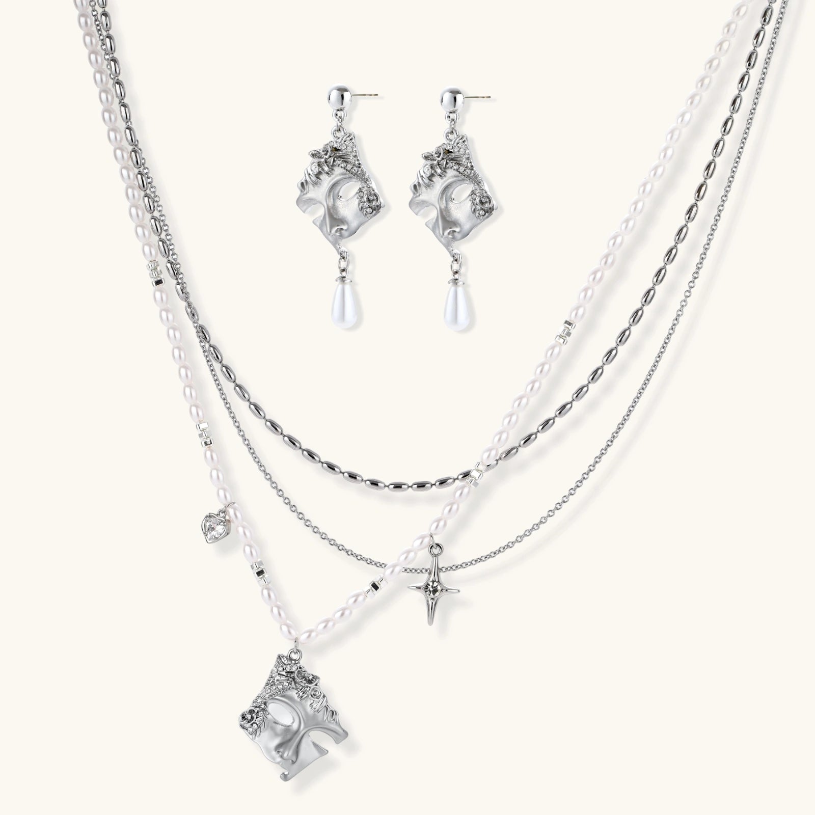 Ornate silver-toned masquerade mask jewelry set featuring rhinestone details and pearl drop earrings on white background.