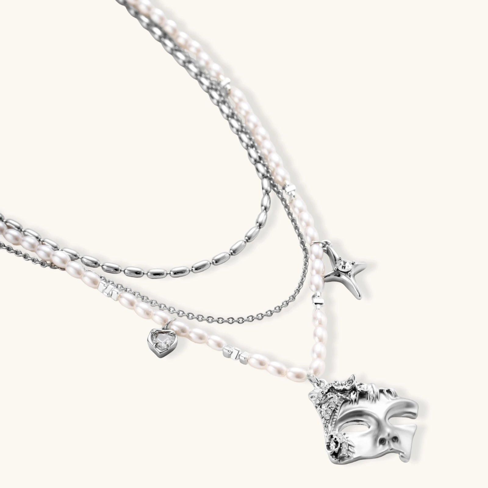 Ornate silver-toned masquerade mask jewelry set featuring rhinestone details and pearl drop earrings on white background.