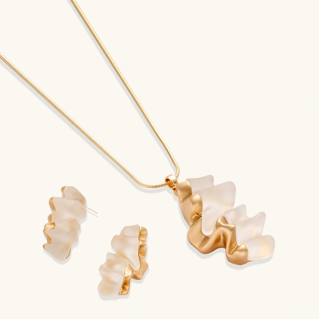 Sculptural gold-toned jewelry set featuring wavy organic earrings and matching necklace pendant with translucent resin accents.