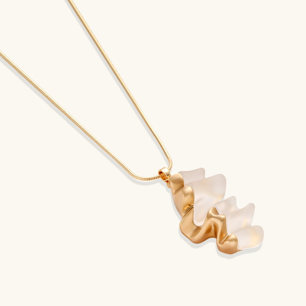 Sculptural gold-toned jewelry set featuring wavy organic earrings and matching necklace pendant with translucent resin accents.