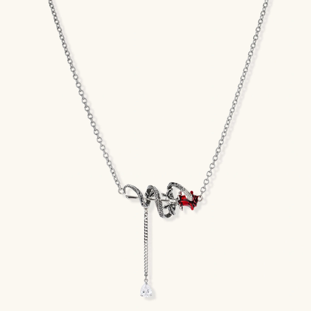 Gothic jewelry set with silver snake designs holding red enamel roses, featuring detailed leaf stems on cream background