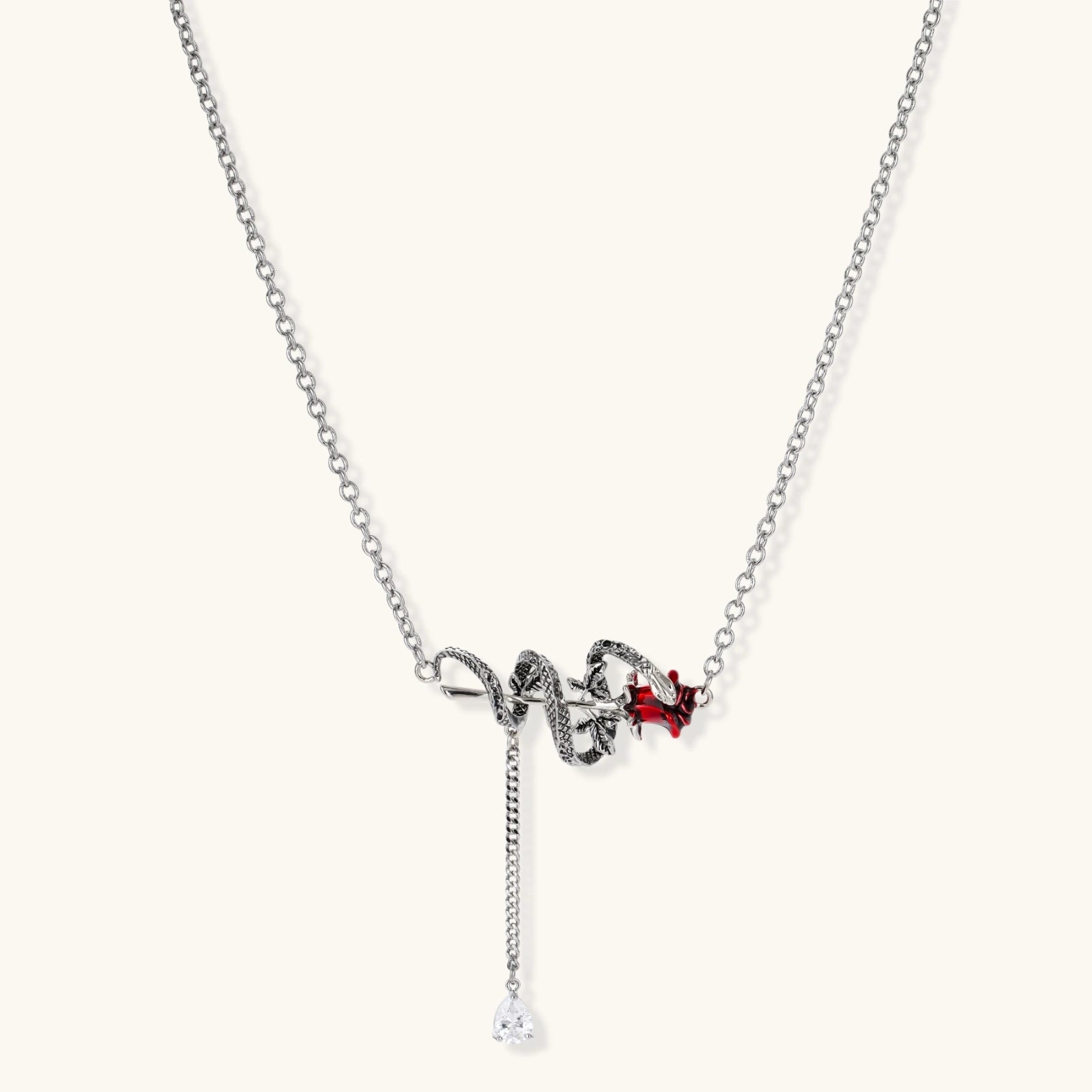 Gothic jewelry set with silver snake designs holding red enamel roses, featuring detailed leaf stems on cream background