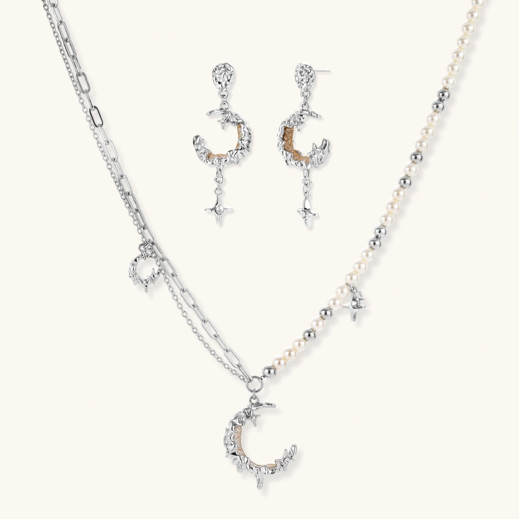 Mixed-metal jewelry set featuring layered necklaces with crescent moon pendant and pearl beads, plus matching star-drop earrings.