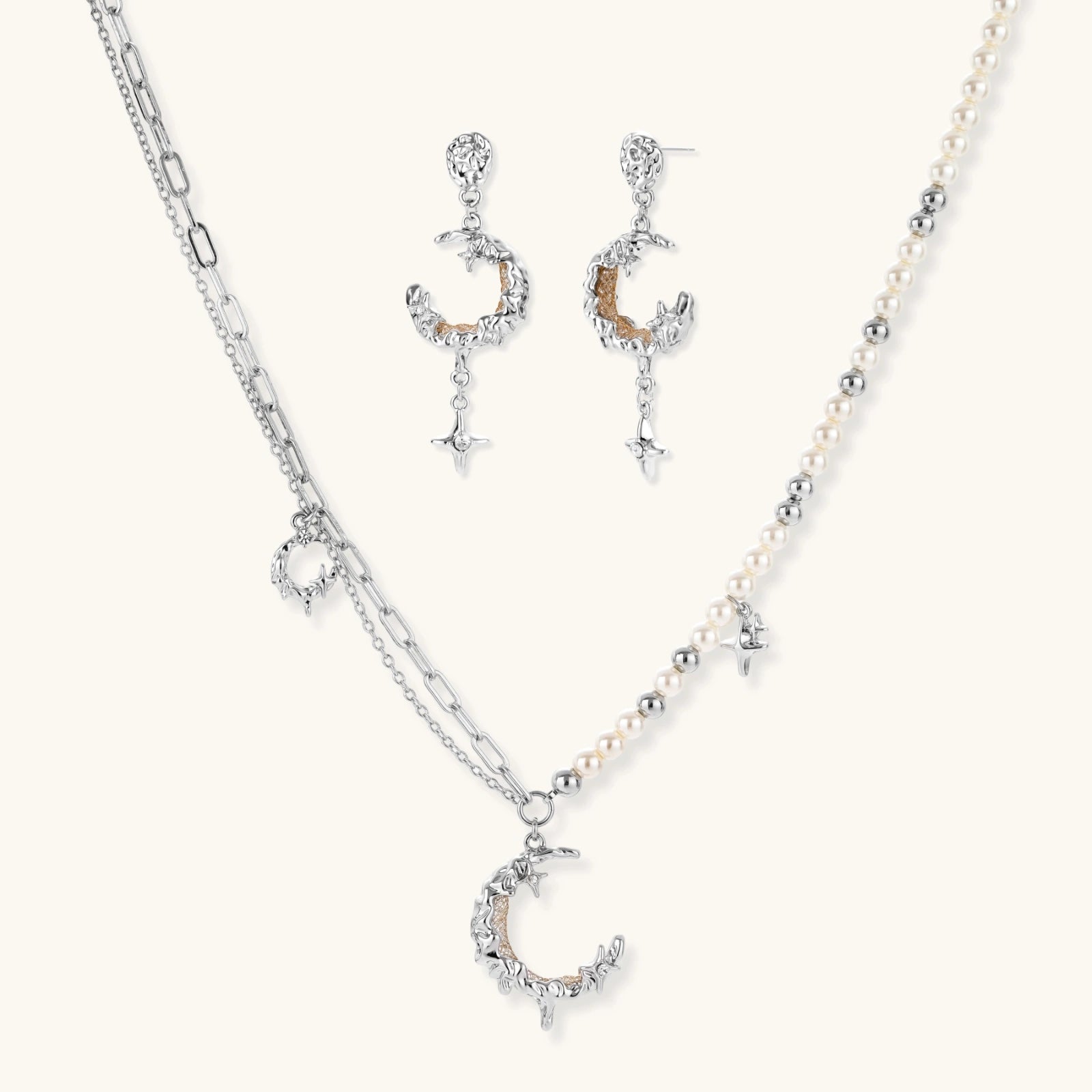 Mixed-metal jewelry set featuring layered necklaces with crescent moon pendant and pearl beads, plus matching star-drop earrings.