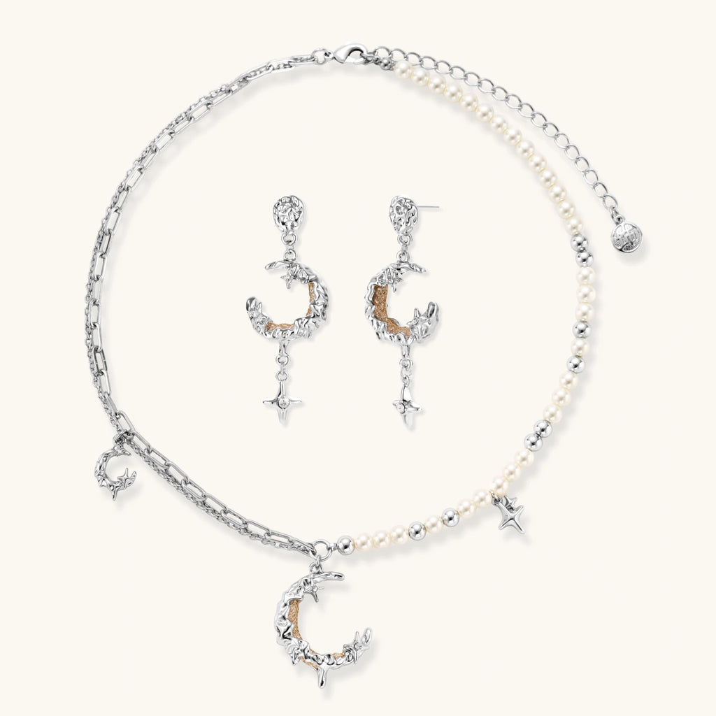 Mixed-metal jewelry set featuring layered necklaces with crescent moon pendant and pearl beads, plus matching star-drop earrings.