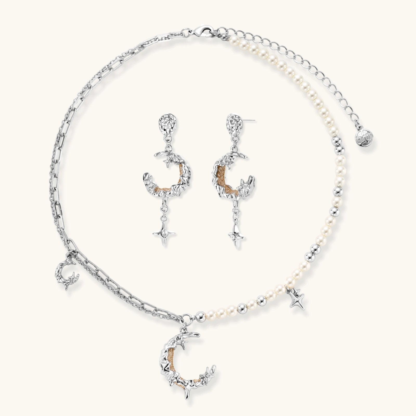 Mixed-metal jewelry set featuring layered necklaces with crescent moon pendant and pearl beads, plus matching star-drop earrings.