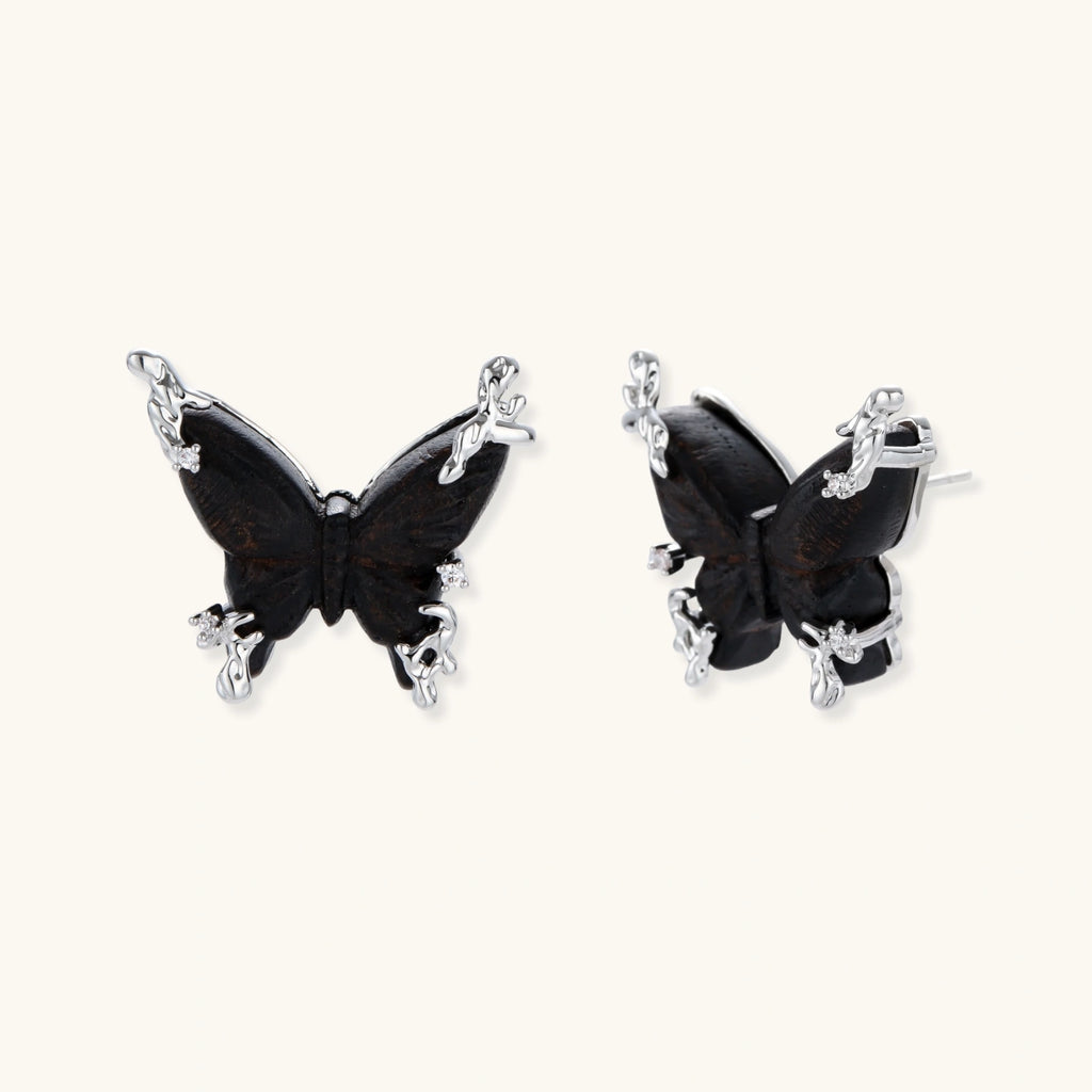 Dark wood butterfly earrings and necklace with silver chain accents on white background, showing natural grain texture.