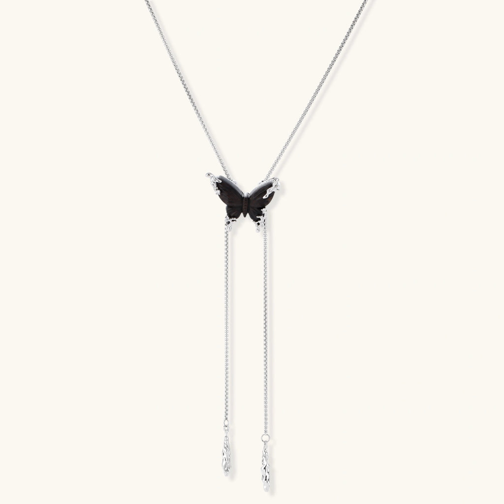 Dark wood butterfly earrings and necklace with silver chain accents on white background, showing natural grain texture.