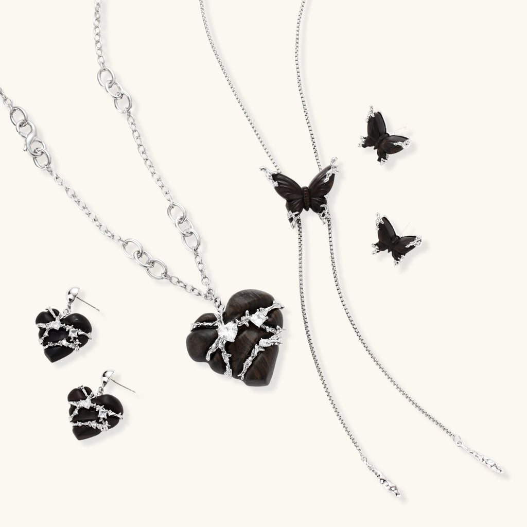 Dark wood butterfly earrings and necklace with silver chain accents on white background, showing natural grain texture.