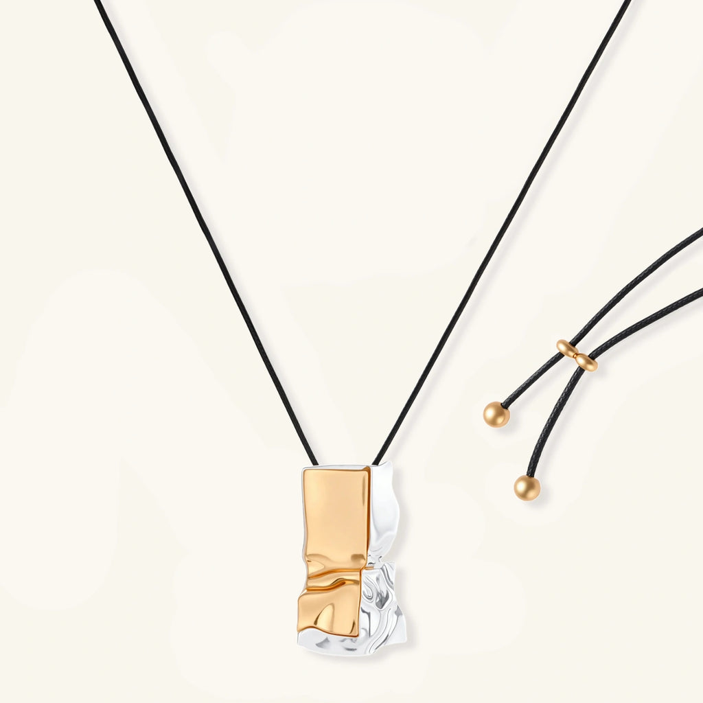 Abstract sculptural pendant necklace with gold and silver toned eco-zinc alloy on black adjustable cord with brass bead details