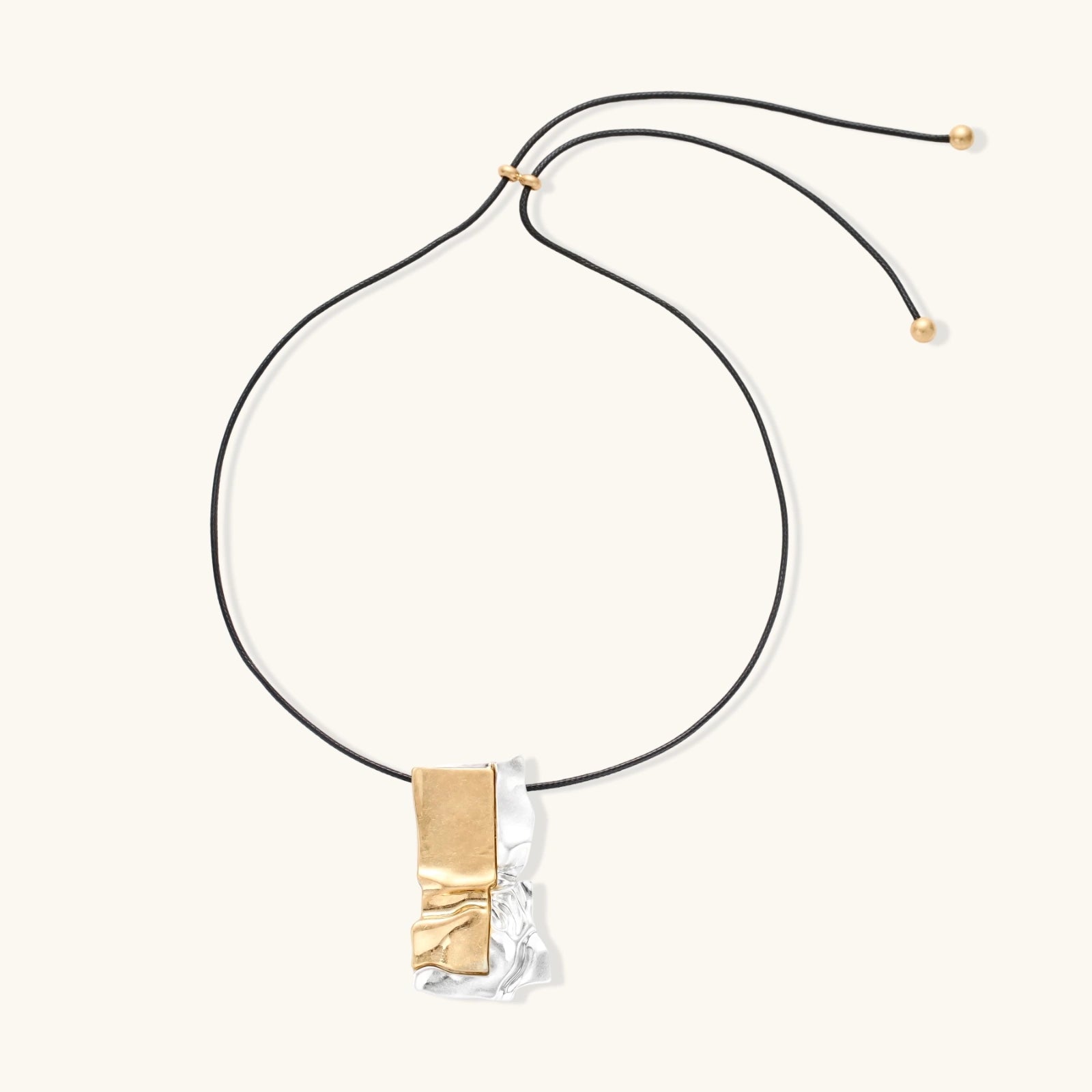 Abstract sculptural pendant necklace with gold and silver toned eco-zinc alloy on black adjustable cord with brass bead details