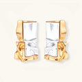 Close-up of avant-garde sculptural earrings with flowing liquid metal design in gold and silver tones on white background.