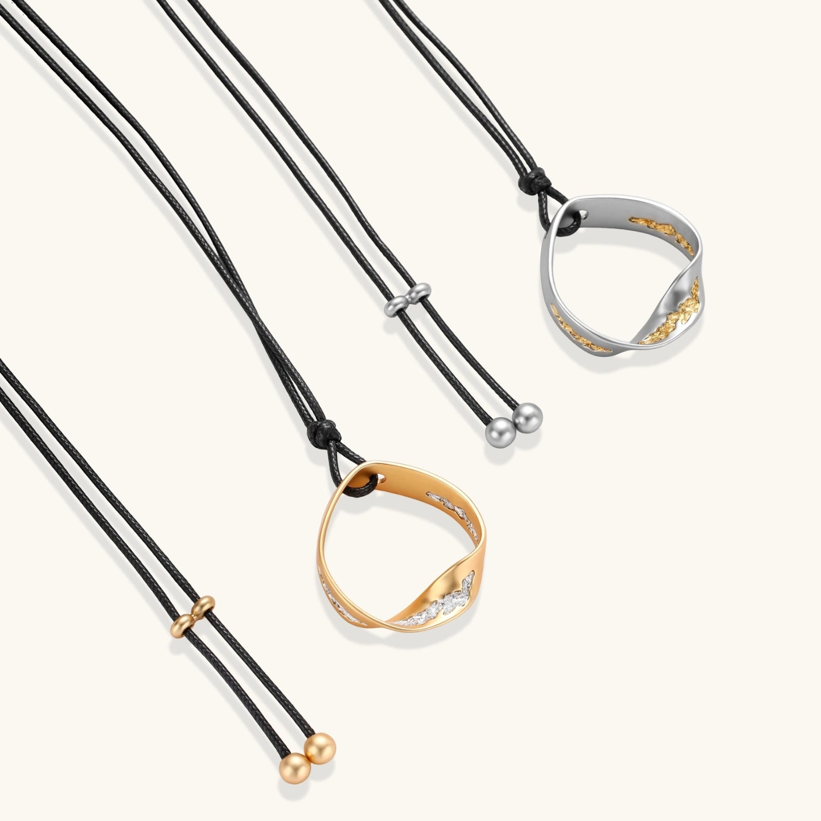 Adjustable black cord necklace with circular gold pendant featuring sparkly crystal accents on white background.