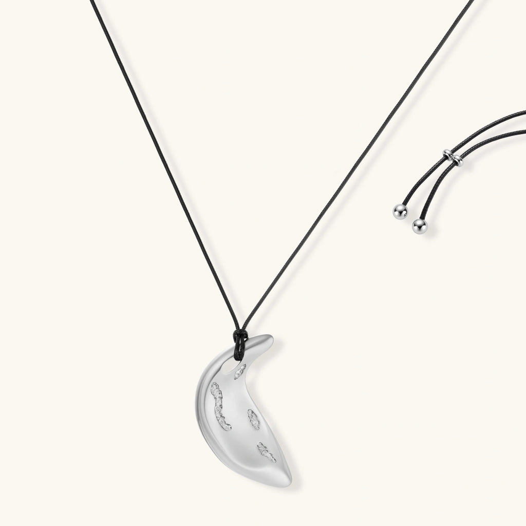 Adjustable crescent moon pendant necklace in gold and silver eco-zinc alloy with decorative engravings on black cord