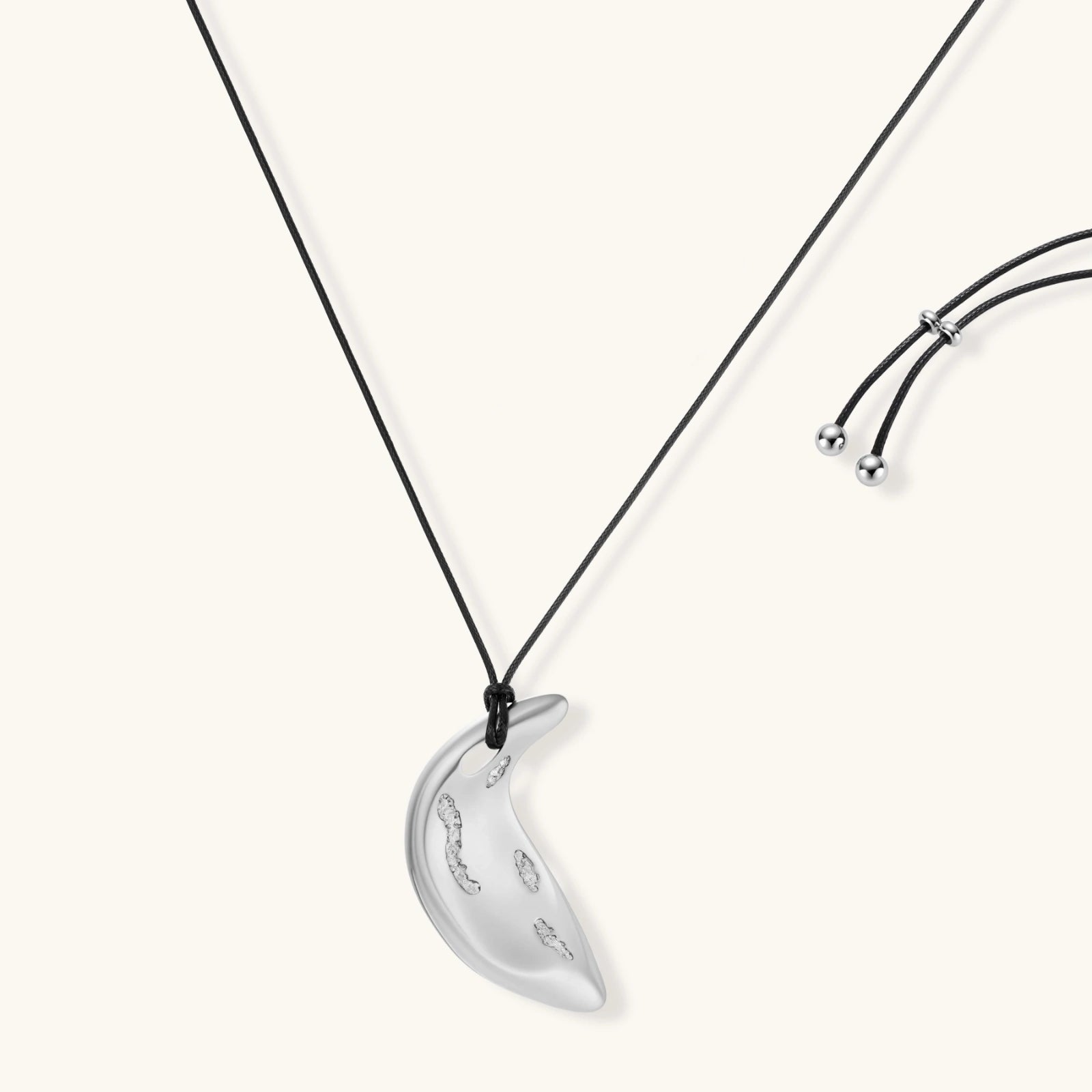 Adjustable crescent moon pendant necklace in gold and silver eco-zinc alloy with decorative engravings on black cord