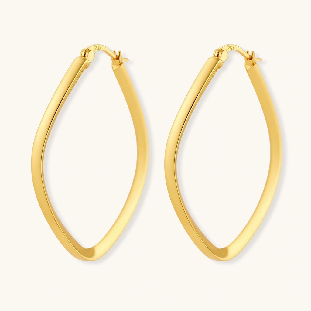 Set of geometric gold-plated sterling silver hoop earrings in oval and cushion shapes on cream background