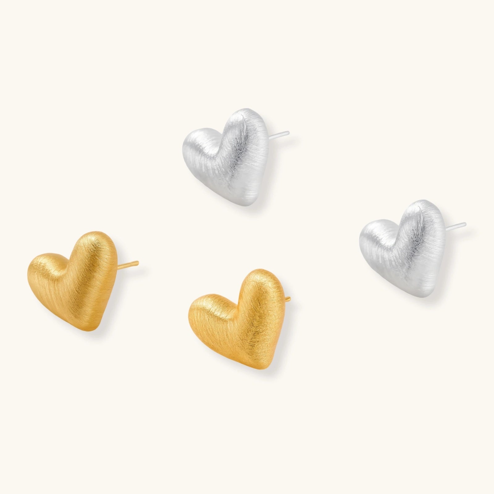 Pair of textured heart-shaped stud earrings in brushed platinum-plated sterling silver against cream background.