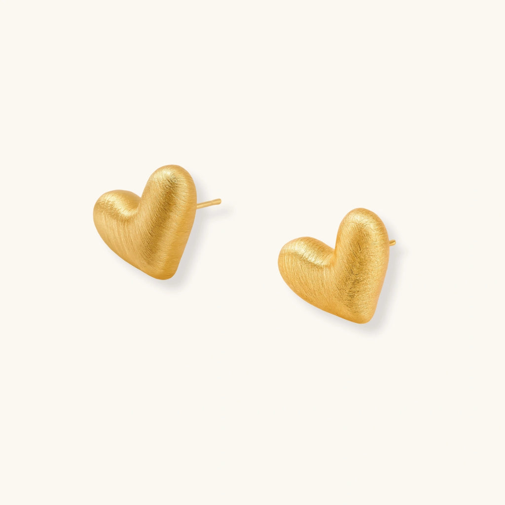 Pair of small heart-shaped stud earrings with brushed metallic finish, showing both silver and gold variants on neutral background.