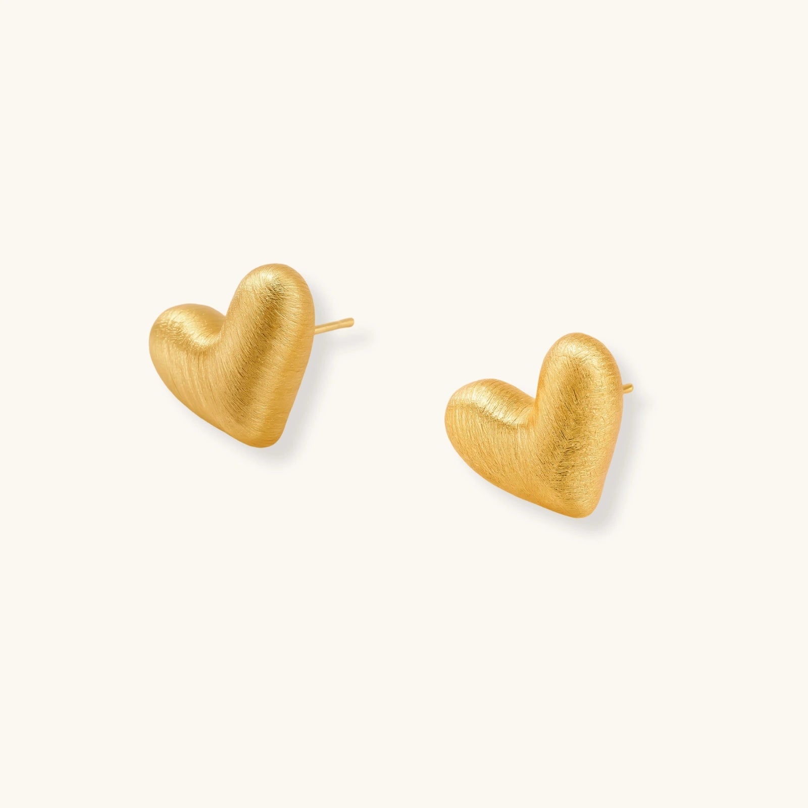 Pair of small heart-shaped stud earrings with brushed metallic finish, showing both silver and gold variants on neutral background.