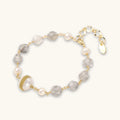 Bracelet with cloudy quartz beads, freshwater pearls, and gold-wrapped baroque pearl centerpiece on white background.