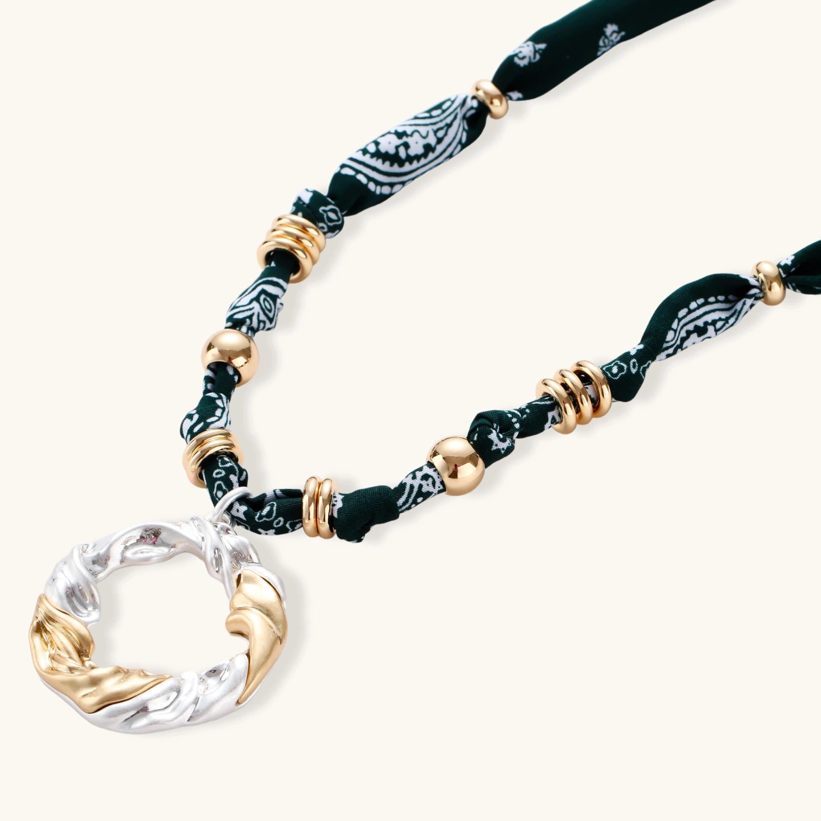 Adjustable necklace with black paisley fabric cord, gold metal spacers, and clear twisted pendant on cream background