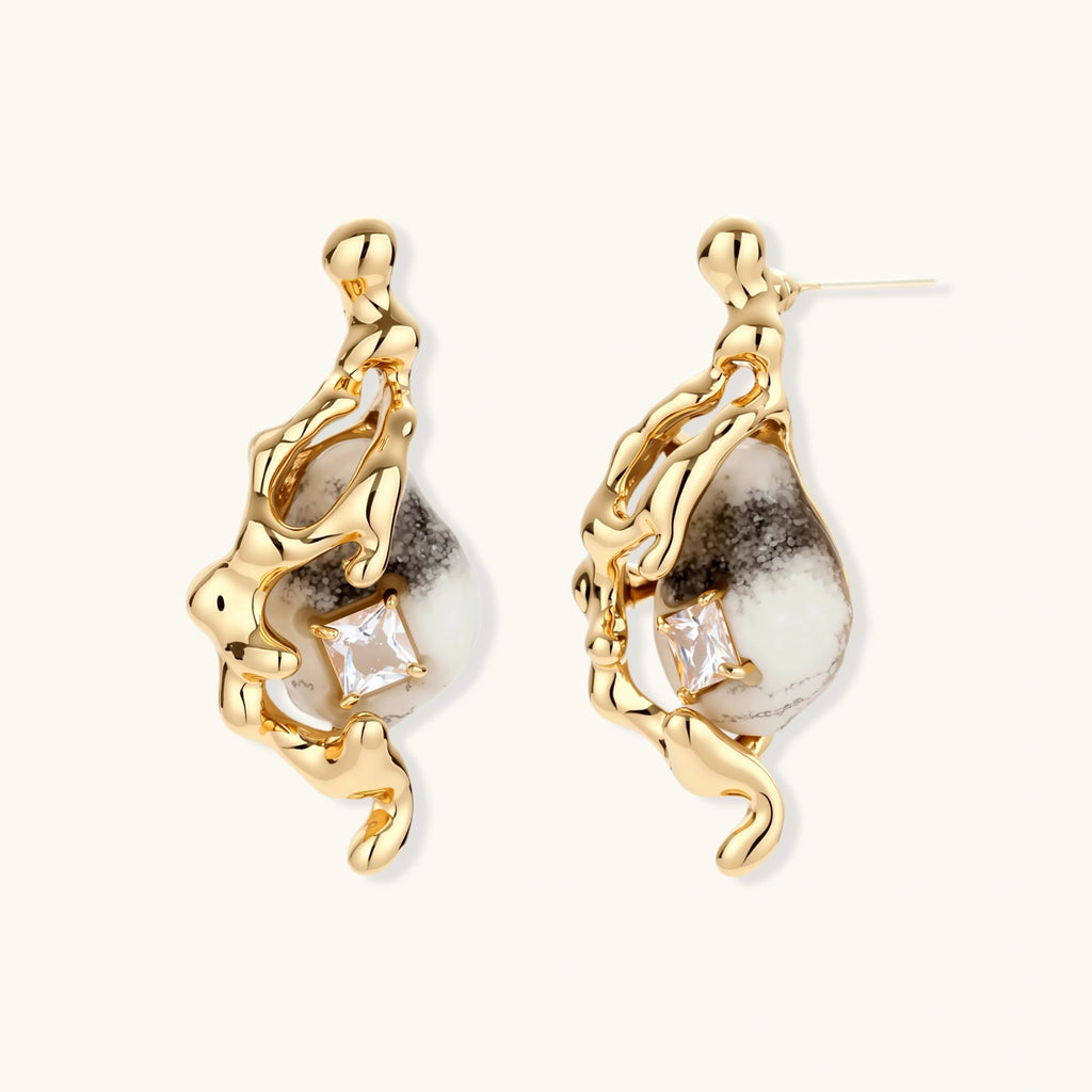 Close-up of metallic dragon-wrapped earrings with marbled resin stones on white background