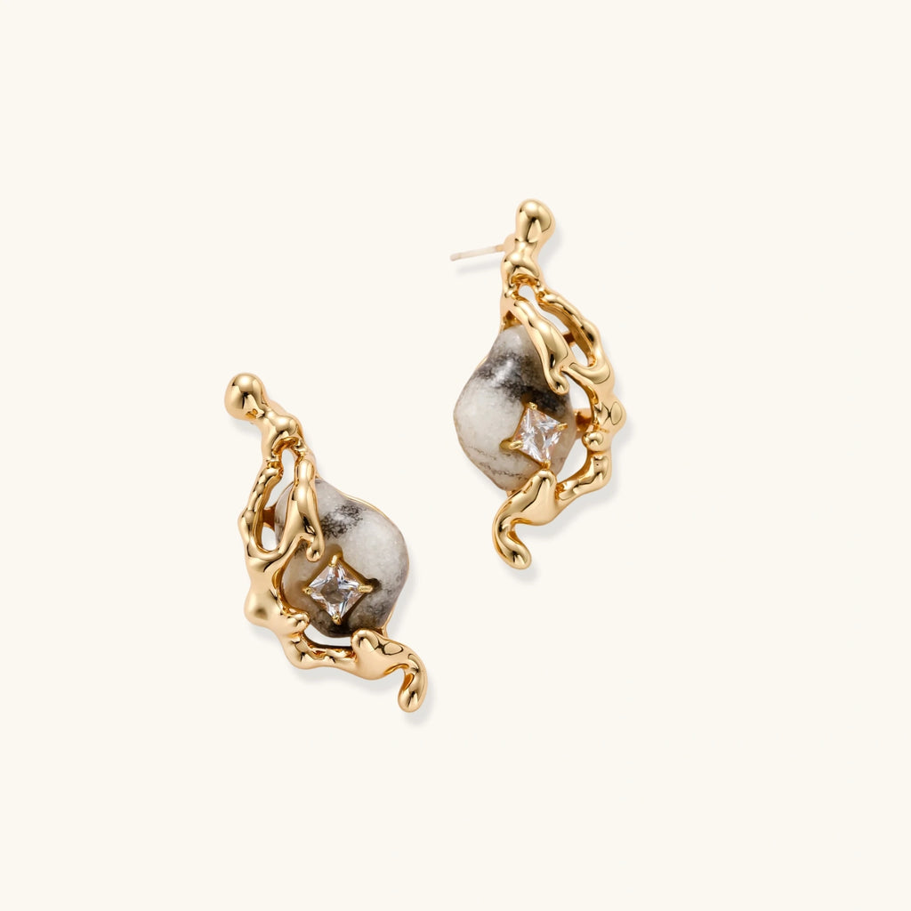 Close-up of metallic dragon-wrapped earrings with marbled resin stones on white background