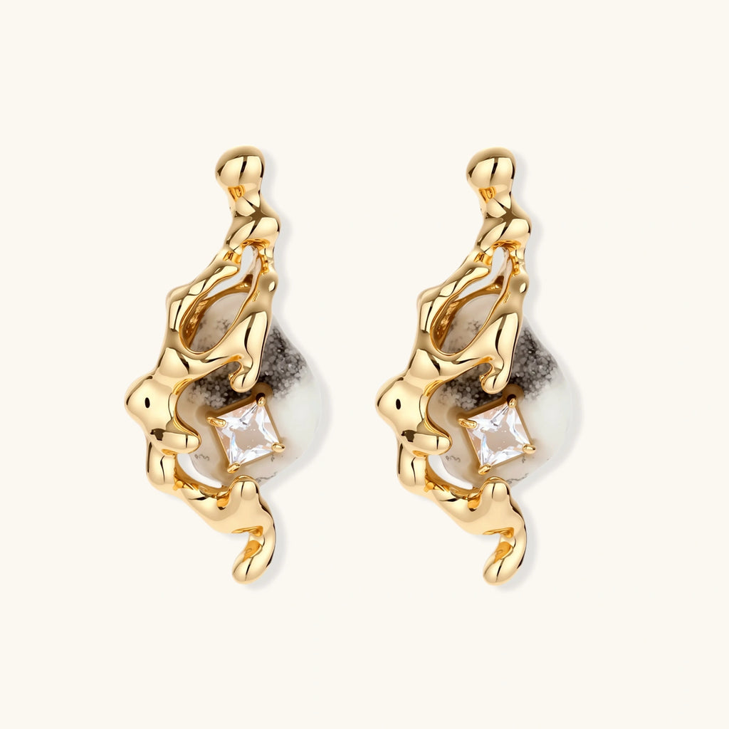 Close-up of metallic dragon-wrapped earrings with marbled resin stones on white background