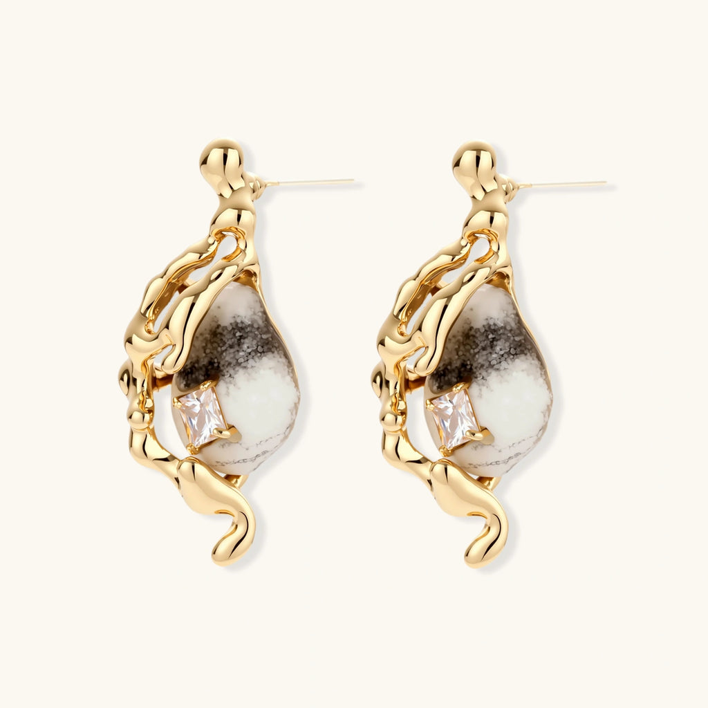 Close-up of metallic dragon-wrapped earrings with marbled resin stones on white background