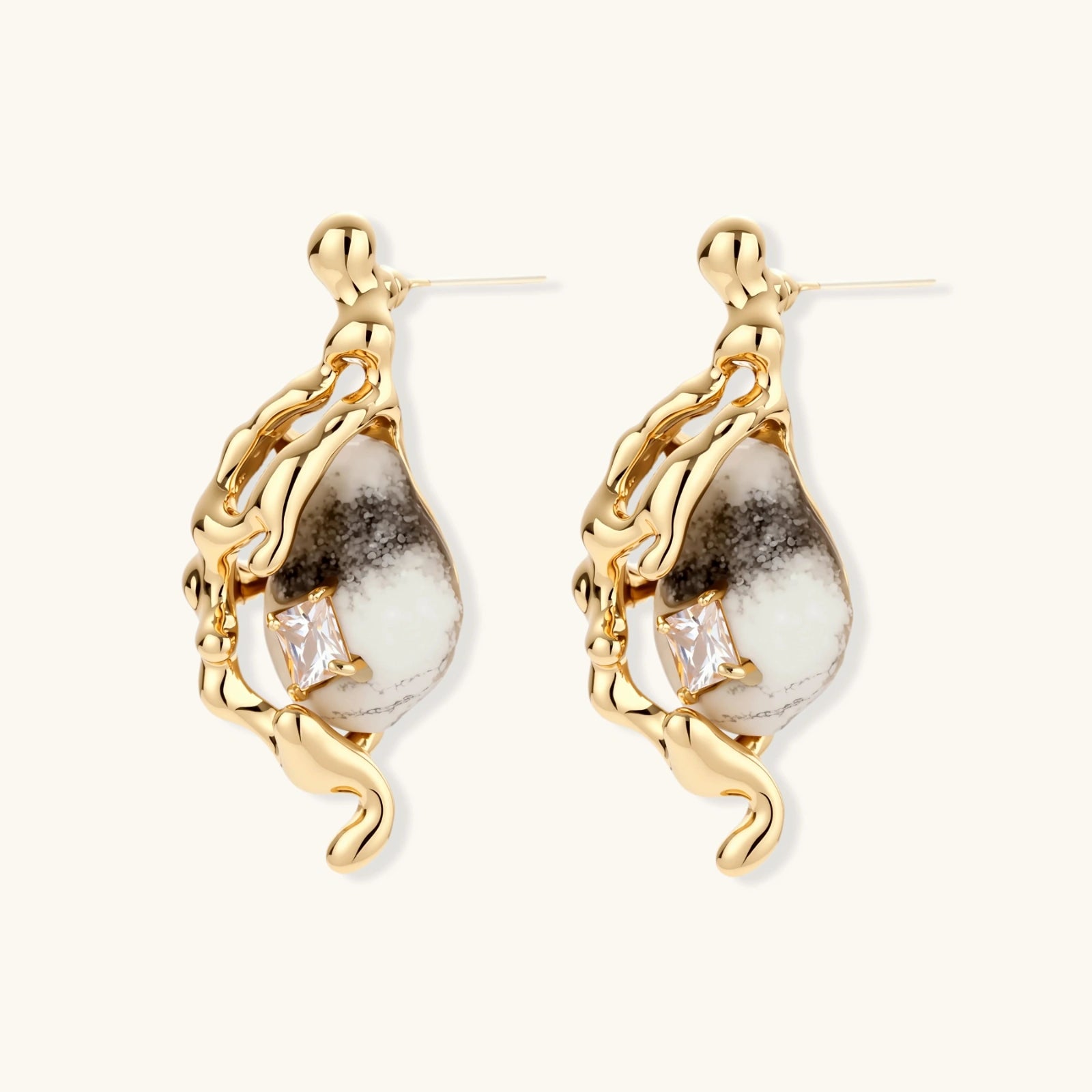 Close-up of metallic dragon-wrapped earrings with marbled resin stones on white background