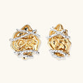 Sculptural rose-shaped stud earrings in gold with silver wire details and S925 posts on cream background.