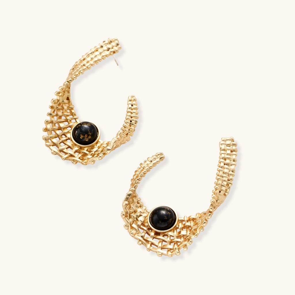 Gold-tone sculptural earrings with interwoven mesh design and black resin stone accents on white background.