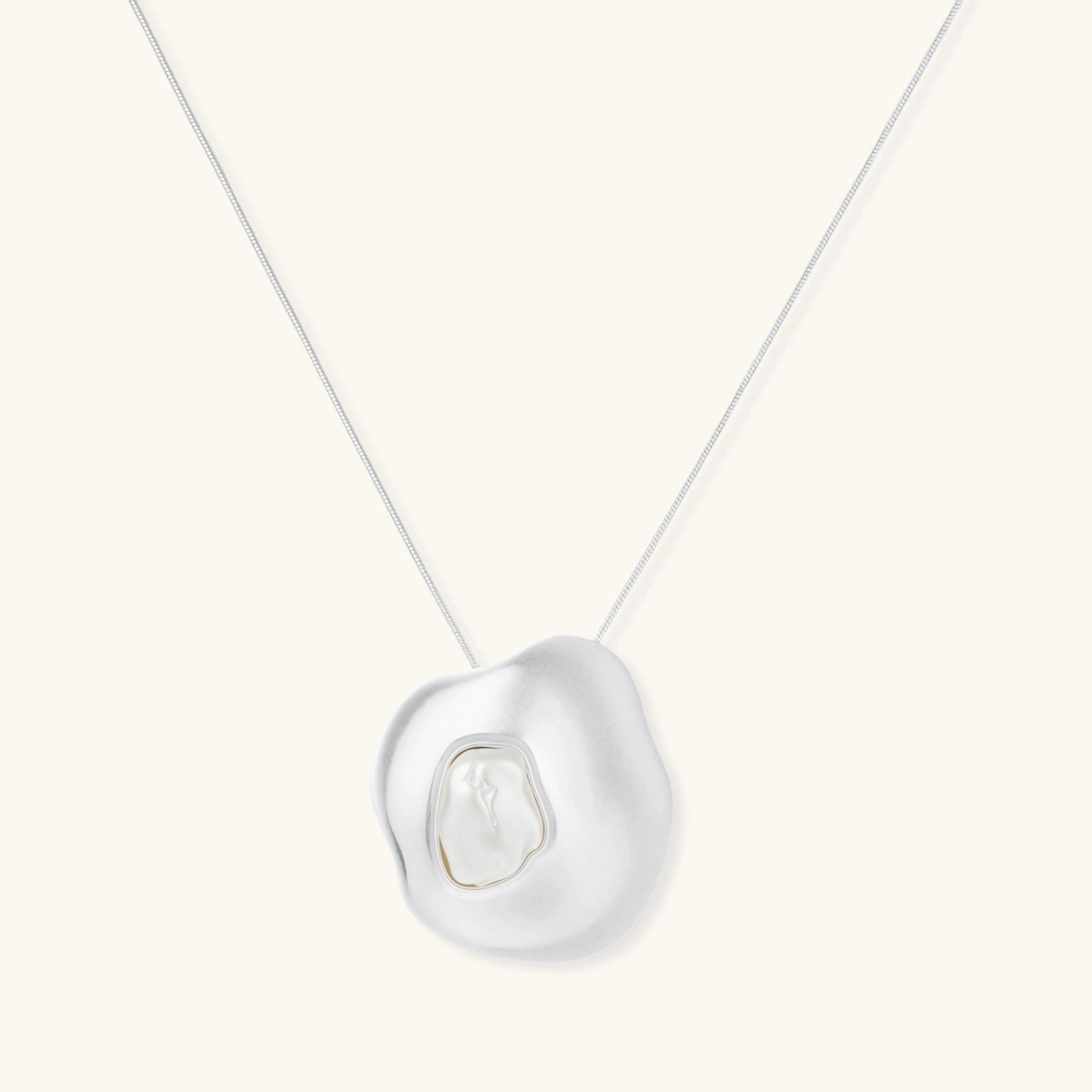 Sculptural silver necklace with flowing organic pendant featuring centered baroque pearl on white background.
