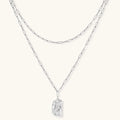 Silver layered necklace with organic flowing pendant in eco-zinc alloy on neutral background, showing adjustable chain design.
