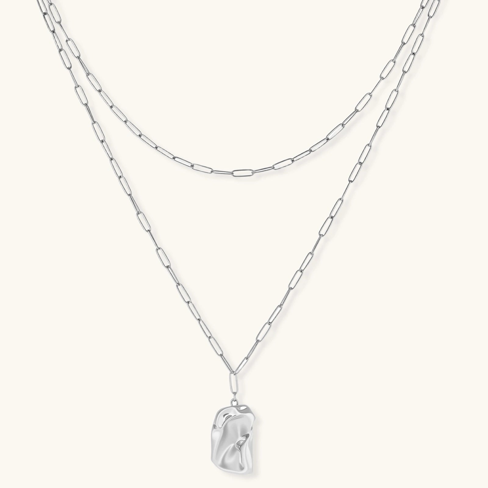 Silver layered necklace with organic flowing pendant in eco-zinc alloy on neutral background, showing adjustable chain design.