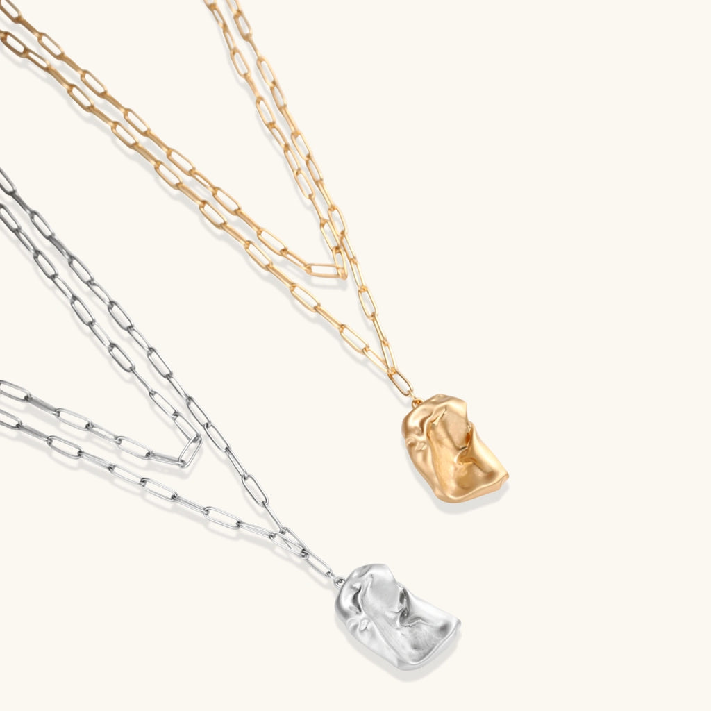Silver layered necklace with organic flowing pendant in eco-zinc alloy on neutral background, showing adjustable chain design.